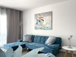 a living room with a blue couch and a sailboat on a painting at Paradise Palms I Deluxe, incl. Welcome Package in Corralejo