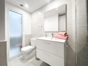 a white bathroom with a toilet and a sink at Paradise Palms I Deluxe, incl. Welcome Package in Corralejo