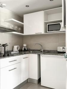 a white kitchen with a sink and a microwave at Paradise Palms I Deluxe, incl. Welcome Package in Corralejo