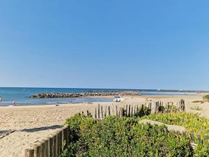 a beach with a wooden fence and the ocean at La p'tite cabane - Maisonnette Carnon Plage in Carnon-Plage