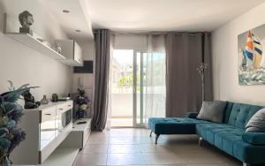 a living room with a blue couch and a window at Paradise Palms I Deluxe, incl. Welcome Package in Corralejo