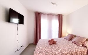 a bedroom with a bed with a television on the wall at Paradise Palms I Deluxe, incl. Welcome Package in Corralejo