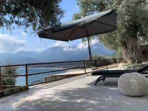 un banc avec un parasol installé sur une terrasse dans l'établissement Waterview Villa, à Chrysi Ammoudia