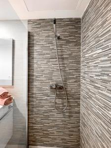 a bathroom with a shower with a tile wall at Paradise Palms I Deluxe, incl. Welcome Package in Corralejo