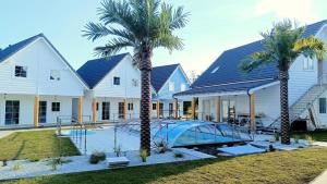 a house with a swimming pool and two palm trees at Bobolin-Ferienhäuser Palm Paradise in Bobolin