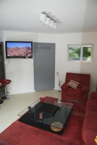 ein Wohnzimmer mit einem roten Sofa und einem Glastisch in der Unterkunft Gîte La Terrasse Du Verger in Carquefou