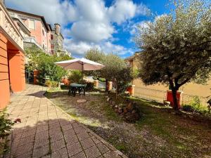 un patio con un ombrellone, un tavolo e un albero di Il giardino degli ulivi a Levanto