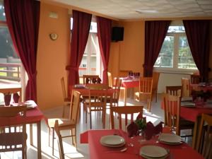 a restaurant with red tables and chairs and windows at Hotel Campestre Chamuiñas in Sanxenxo