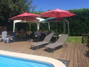 a patio with umbrellas and chairs and a pool at French Pyrenees Luxury in Serres-sur-Arget