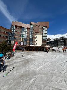 a large building with skis in the snow in front of it at Appartement Eskival skis aux pieds in Val Thorens