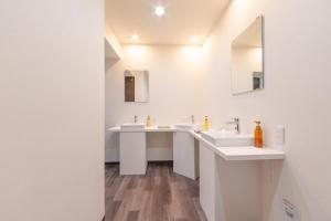 a white bathroom with two sinks and a mirror at Hostel JAQ takamatsu in Takamatsu