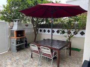 a wooden table with a red umbrella and two chairs at Apartamento Villa Caracol in Cunit