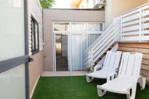 2 sillas blancas en un patio con césped verde en Hadas Villa Spa Yavne'el by Sea N' Rent, en Yavneʼel