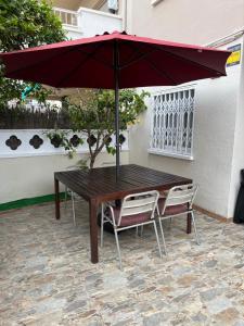 un tavolo in legno e due sedie sotto un ombrellone di Apartamento Villa Caracol a Cunit