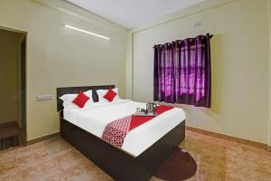 a bedroom with a bed with red pillows at Flagship Honnagiri Residency in Bangalore