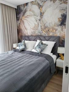 a bedroom with a bed with a painting on the wall at Apartament Jagiełły in Olsztynek