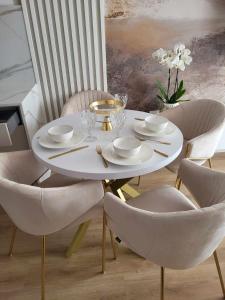 a white dining table and chairs with a white table and chairs at Apartament Jagiełły in Olsztynek