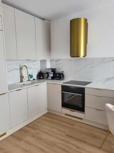 a white kitchen with a sink and a stove at Apartament Jagiełły in Olsztynek
