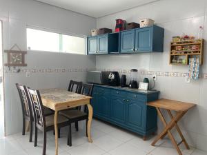 a kitchen with blue cabinets and a table with chairs at Duplex a 10min PP, com Ar, Internet, Estacionamento - Casa236 in Campina Grande