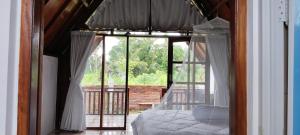 um quarto com uma cama e uma porta de vidro para uma varanda em Nan Bungalows Tetebatu em Tetebatu