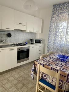 a kitchen with white cabinets and a table and a stove at Dora e Franco Apartment treseiseiseiquattroseicinquezeroottozero in Torre Mozza +14 photos