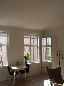 Habitación con 3 ventanas, mesa y sillas en Newly renovated apt in the heart of Grünerløkka, en Oslo