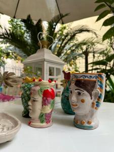 Quatro vasos com caras sentados numa mesa. em Casa Patrizia em Giardini Naxos