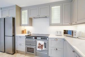 a white kitchen with a stove and a refrigerator at 6 Bedroom and 4 Bath Bedford House + Private Garden in Ruislip
