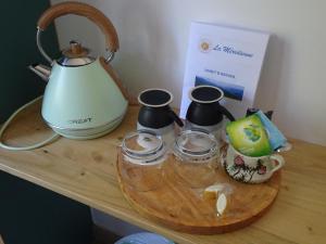 a tea kettle and three cups on a wooden table at La Méridienne - Chambres d'hôtes in Venterol