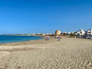 a beach with people on the sand and the water at Dora e Franco Apartment treseiseiseiquattroseicinquezeroottozero in Torre Mozza