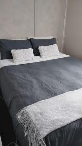 a black and white bed with two pillows on it at Mt Lyll (Back Cabin)@Lettes Bay in Strahan