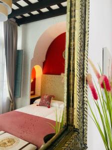 a mirror reflecting a bedroom with a bed in a room at La Gitanilla Alojamiento & Encanto Jerez in Jerez de la Frontera