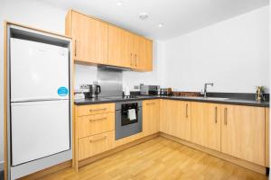 伯明罕的住宿－Birmingham City Centre Deluxe Apartment - Top Rated - 36C，厨房配有木制橱柜和白色冰箱。