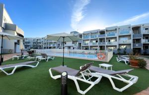 a patio with chaise lounge chairs and a swimming pool at Paradise Palms I Deluxe, incl. Welcome Package in Corralejo