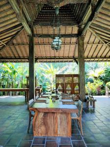 einen großen Holztisch mit Stühlen in einem Pavillon in der Unterkunft Alas Arum Ecolodge in Tabanan