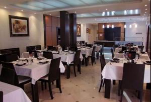 una sala da pranzo con tavoli bianchi e sedie nere di DAR EL IKRAM HOTEL a Alger