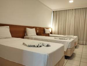 two beds in a hotel room with towels on them at PONTA NEGRA FLAT APART in Natal