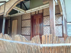 a wooden fence in front of a house with a door at Banamboo in Badian