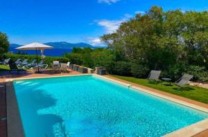 - une piscine avec des chaises et un parasol dans l'établissement Villa U Castellu vue mer imprenable, à Coti-Chiavari