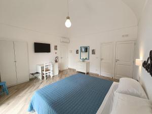 a white bedroom with a blue bed and a tv at Regina Margherita in Positano