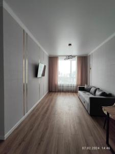 een woonkamer met een bank en een groot raam bij Tandau apartment in Taldykolʼ