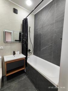 een badkamer met een bad, een wastafel en een douche bij Tandau apartment in Taldykolʼ