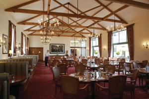 a dining room with tables and chairs and a person at Luton Hoo Hotel, Golf and Spa in Luton