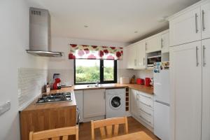 a kitchen with white cabinets and a washer and dryer at The Rocks B&B in Crumlin
