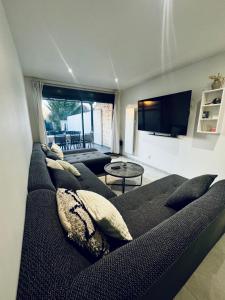 salon z czarną kanapą i telewizorem w obiekcie Maison - Jardin - Terrasse - Netflix - JO 2024 PARIS w mieście Montesson