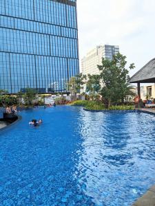 a swimming pool in a city with people in the water at The cozy & luxury room in Podomoro City Deli Medan in Medan