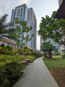 a park with benches and trees and tall buildings at The cozy & luxury room in Podomoro City Deli Medan in Medan