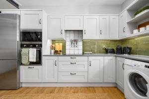 a kitchen with white cabinets and a washer and dryer at 2-Bedroom Cottage - Long Stays Welcome in Cheadle