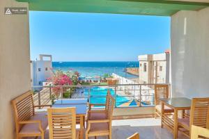 a balcony with tables and chairs and a view of the ocean at Tiba Rose hurghada in Hurghada
