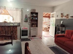 uma sala de estar com um sofá vermelho e uma cozinha em Chácara a 6km do centro! em Poços de Caldas